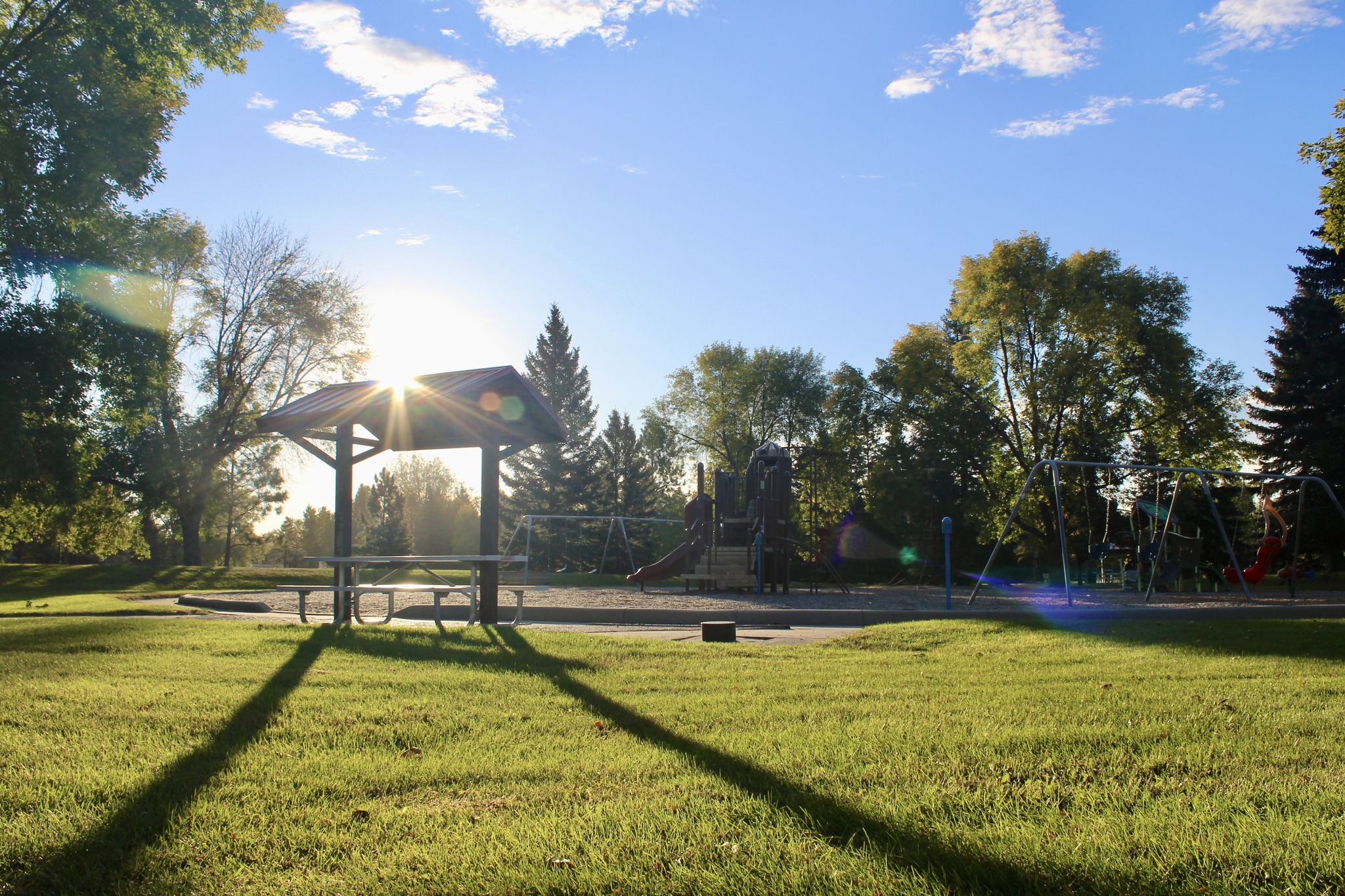 A Grand Forks Park District playground and picnic shelter at golden hour